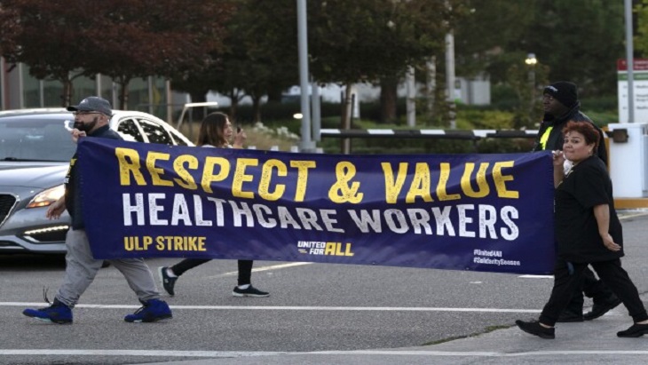 2 healthcare employees carrying a banner